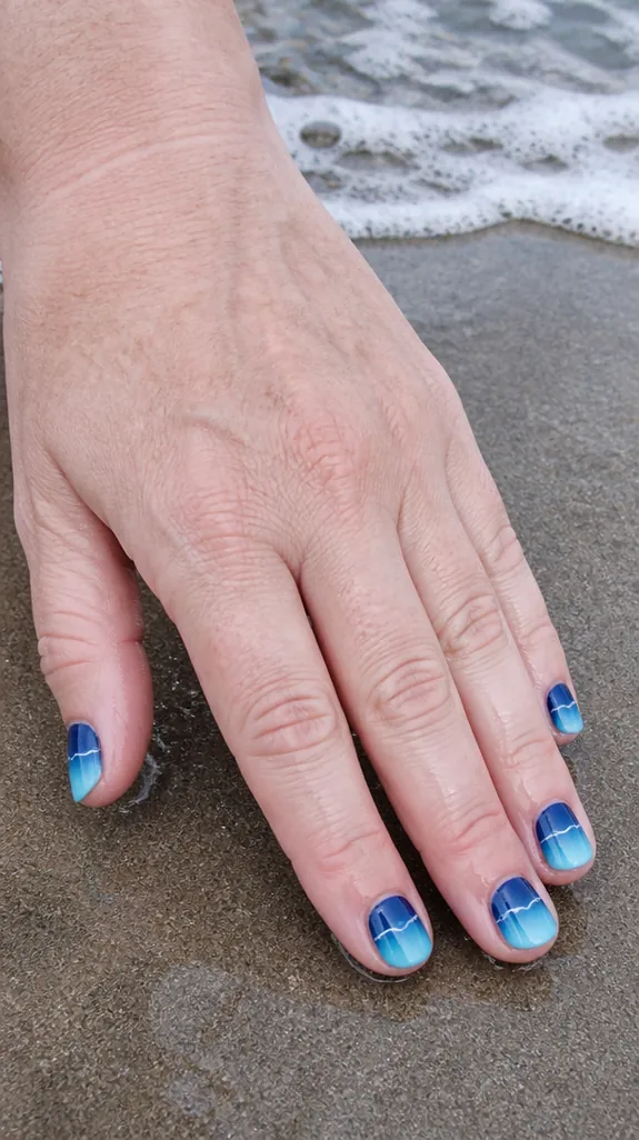 short nails with a deep blue to aqua ombre and a white wave line